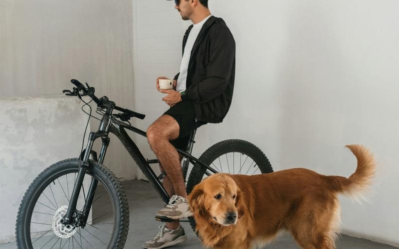 a man sitting on a bike next to a dog